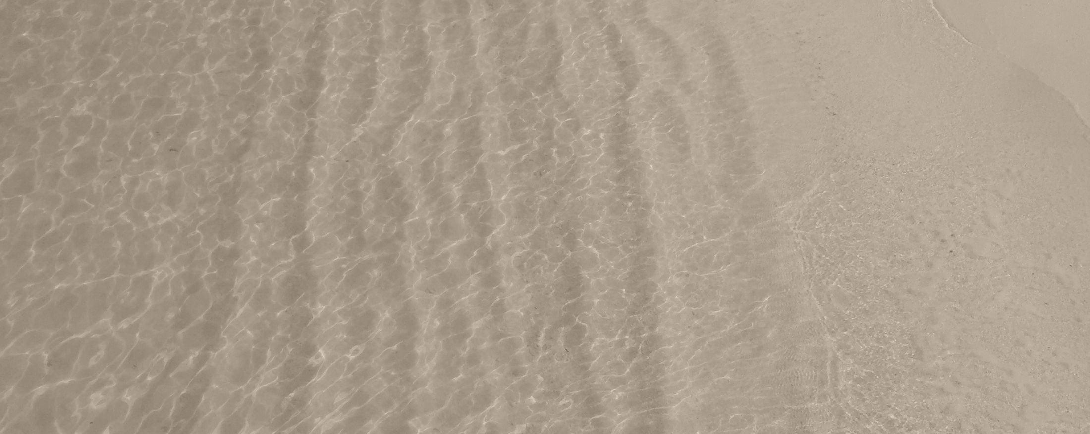 Rippling water on sandy beach surface.