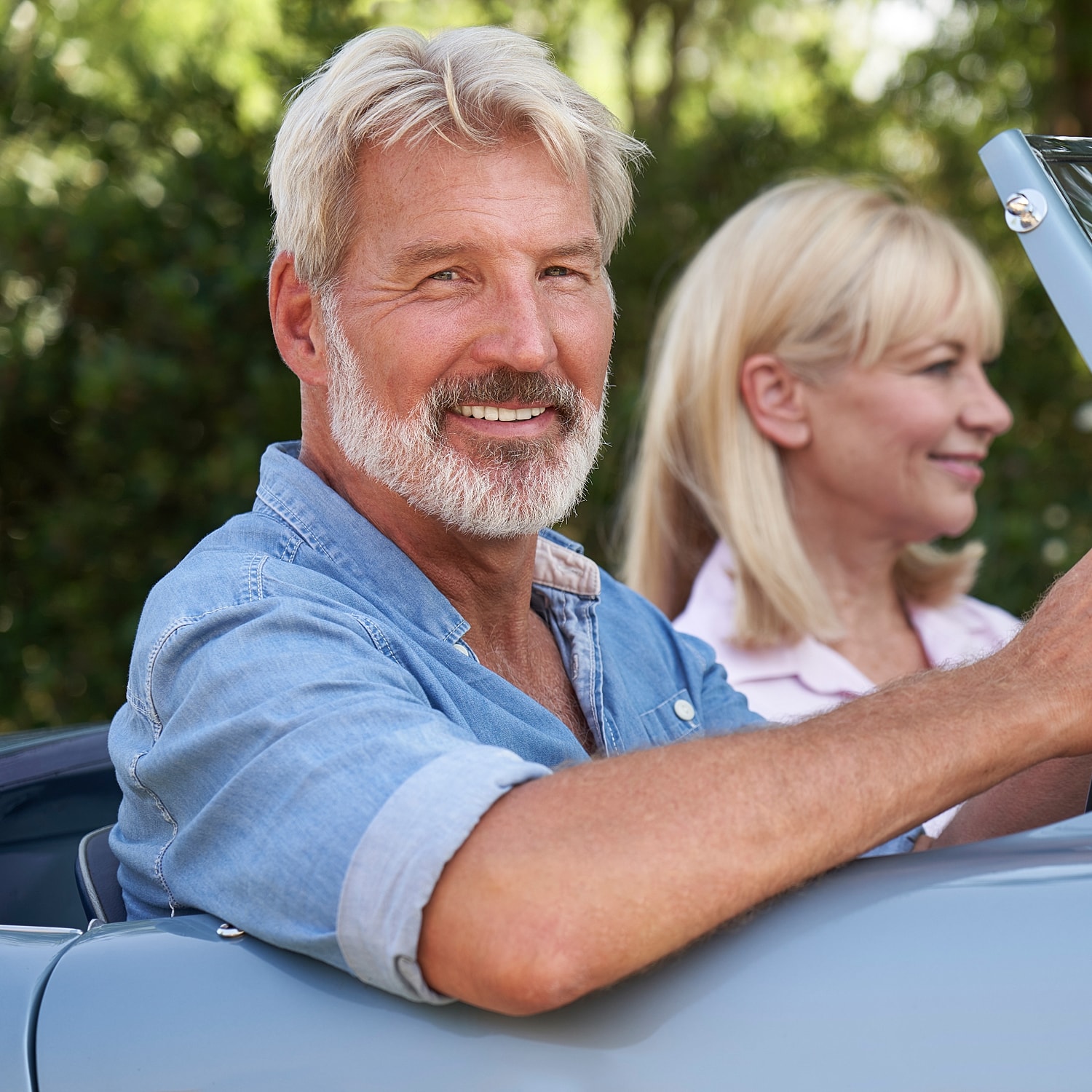 Smiling couple in vintage convertible car.