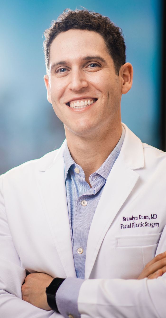 Smiling doctor in a white coat, arms crossed.