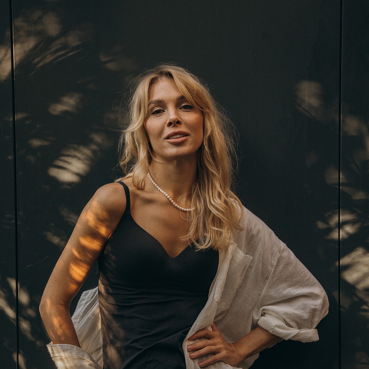 Woman in black dress against dark background.