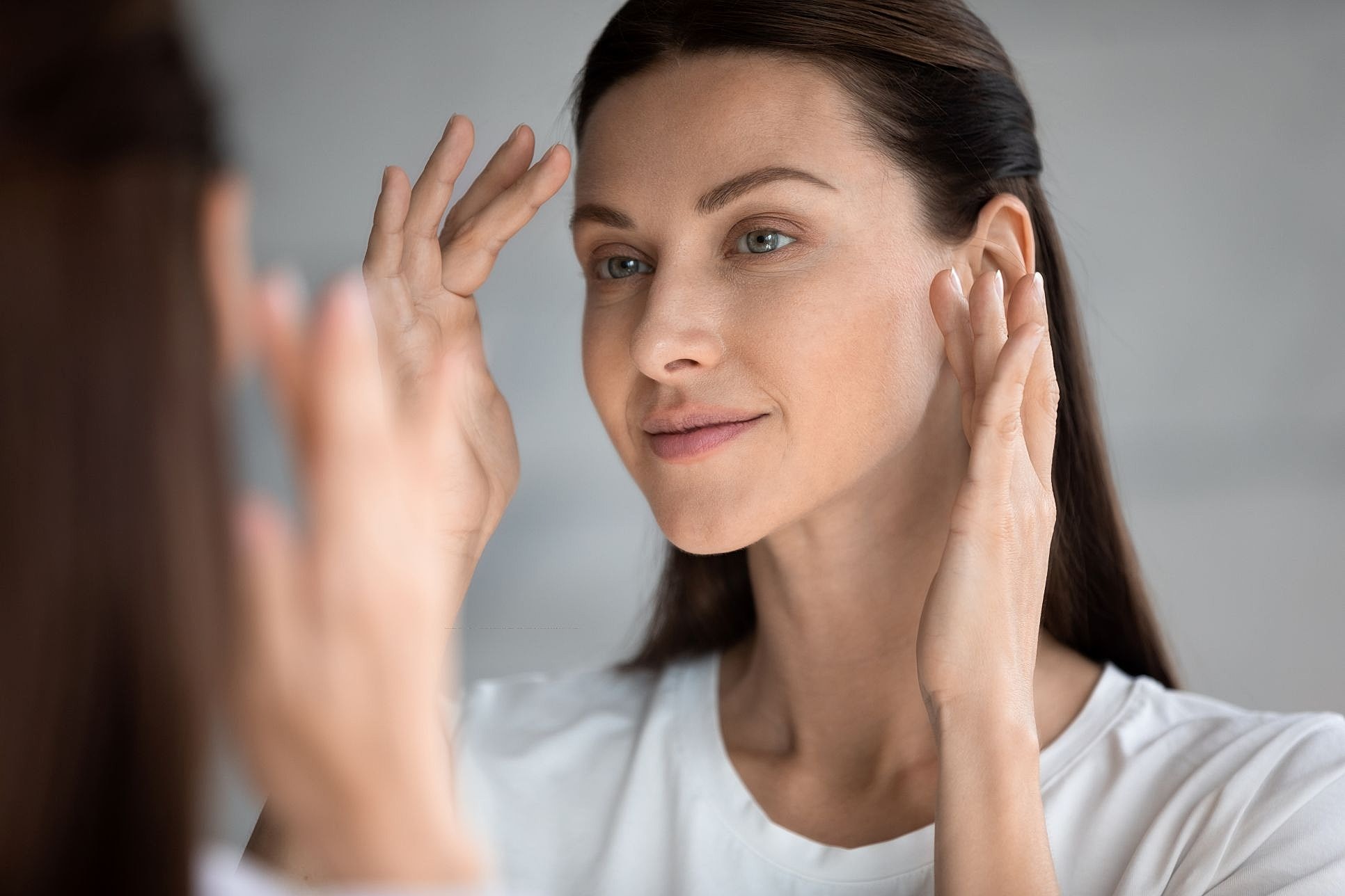 Woman applying skincare while looking in mirror