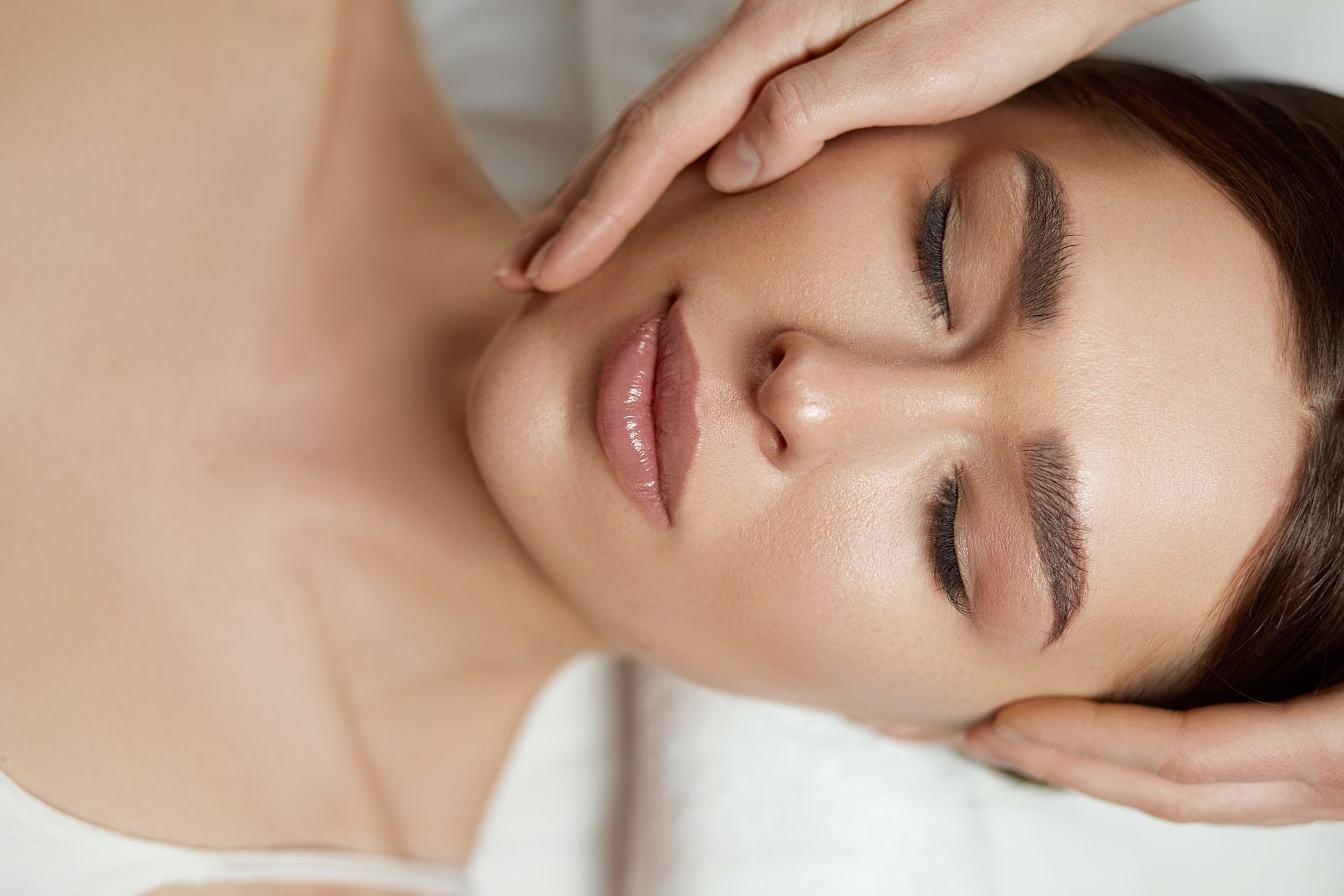 Woman receiving a facial treatment illustrating facial fat grafting and dermal fillers for restoring lost volume.