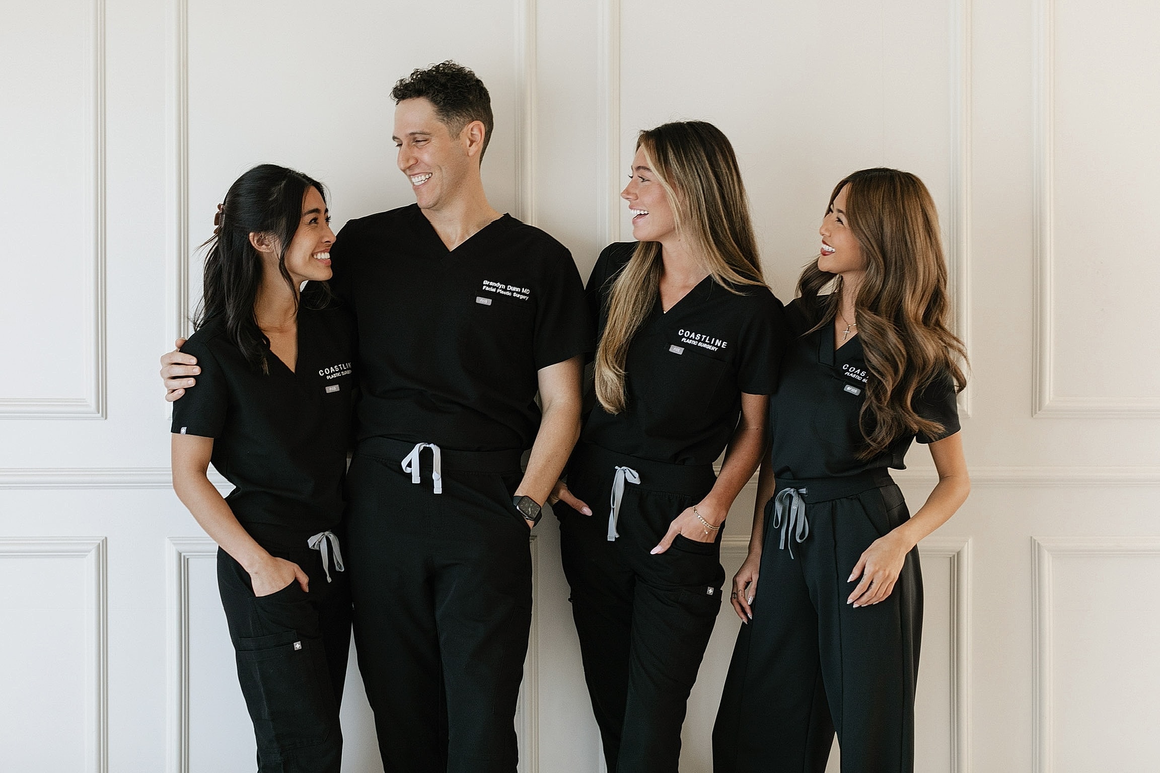 Three medical professionals smiling in office setting.