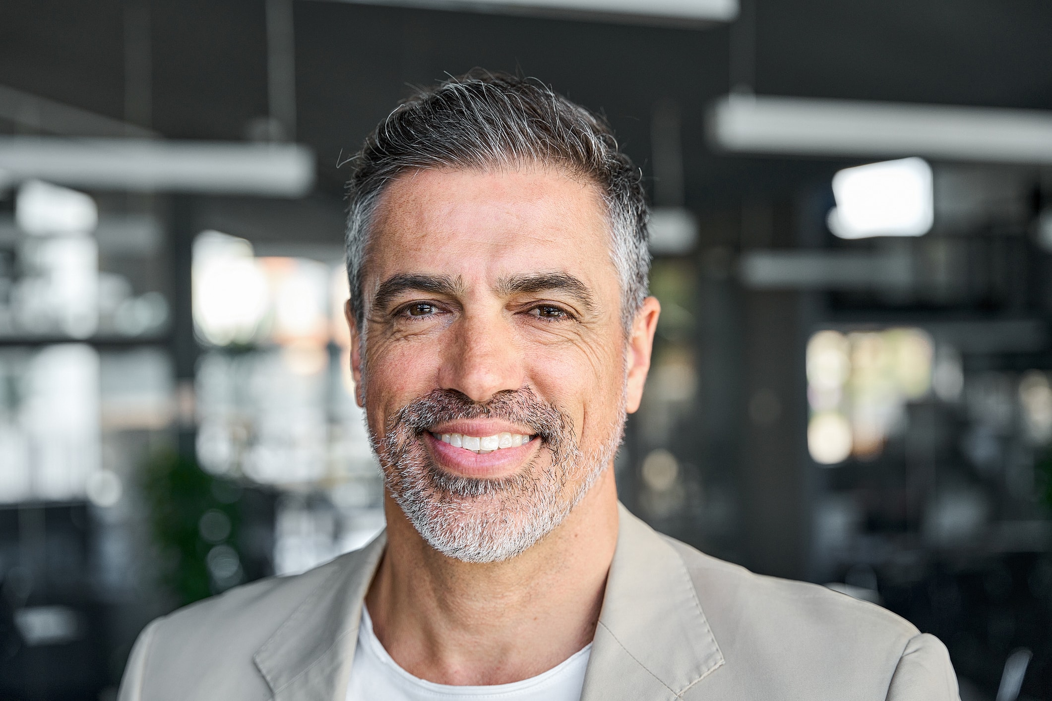 Smiling man in casual attire with gray hair.