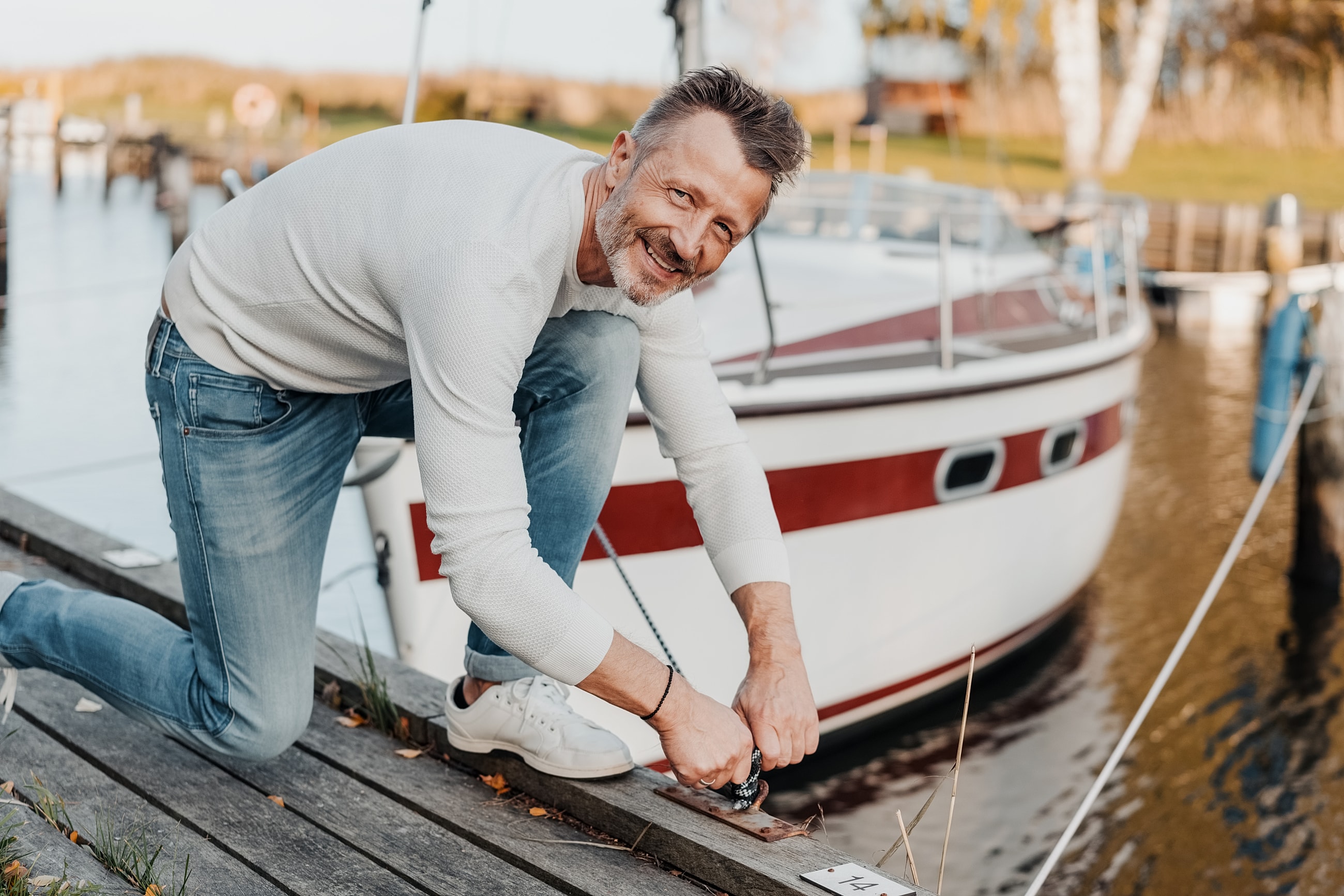 Man tying a rope by a boat.